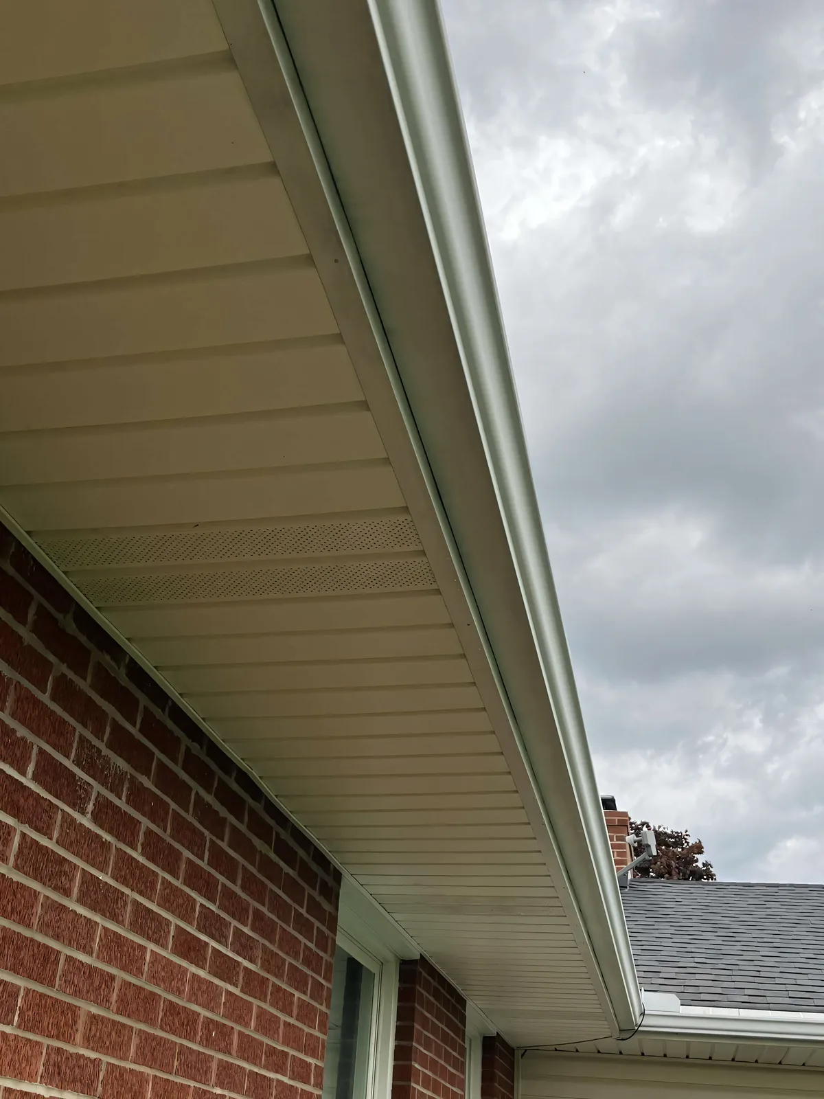 Clean gutters and soffit on a brick home — exterior brightened